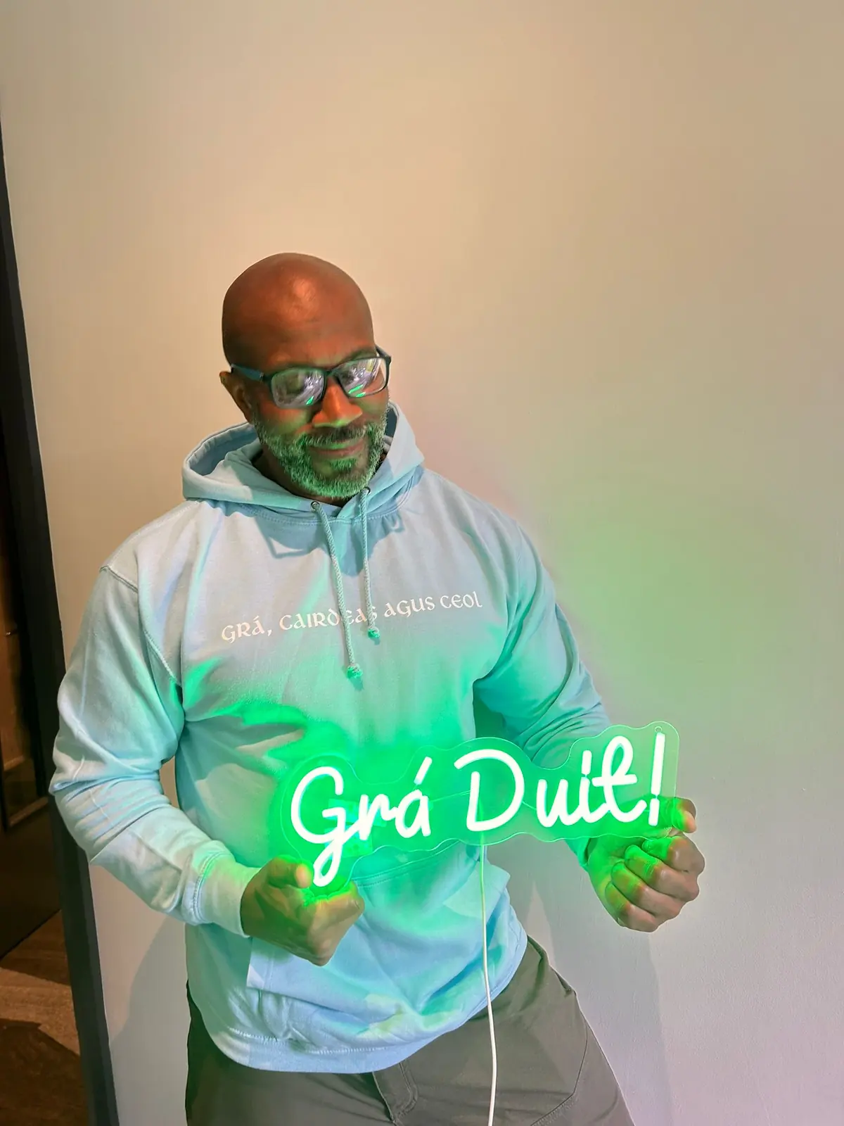 Ice Blue Grá Duit hoodie illuminated by the Grá Duit sign
